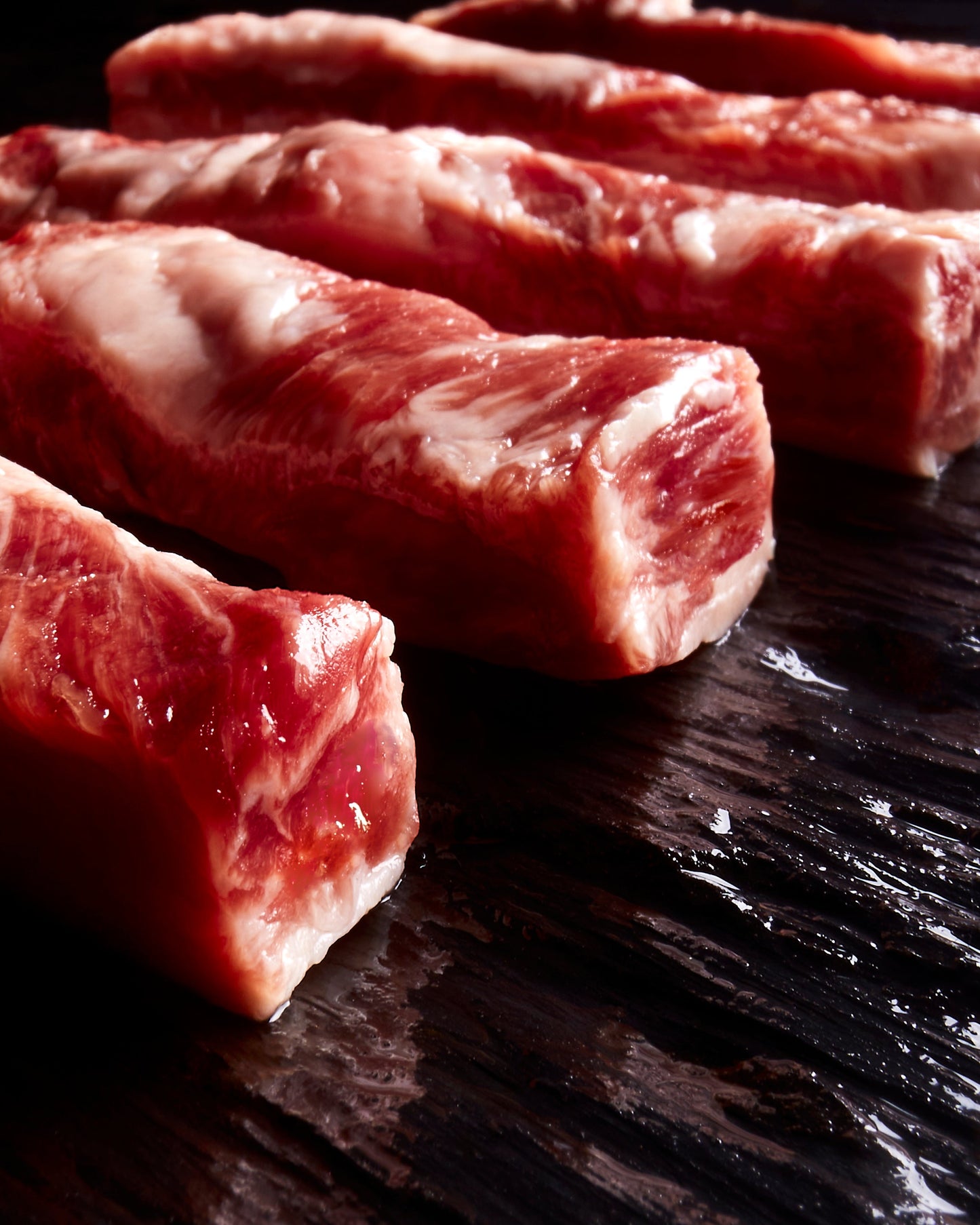 Lágrima Ibérica pork loin rib strips, pasture-raised, showcasing their high fat content and exceptional marbling.